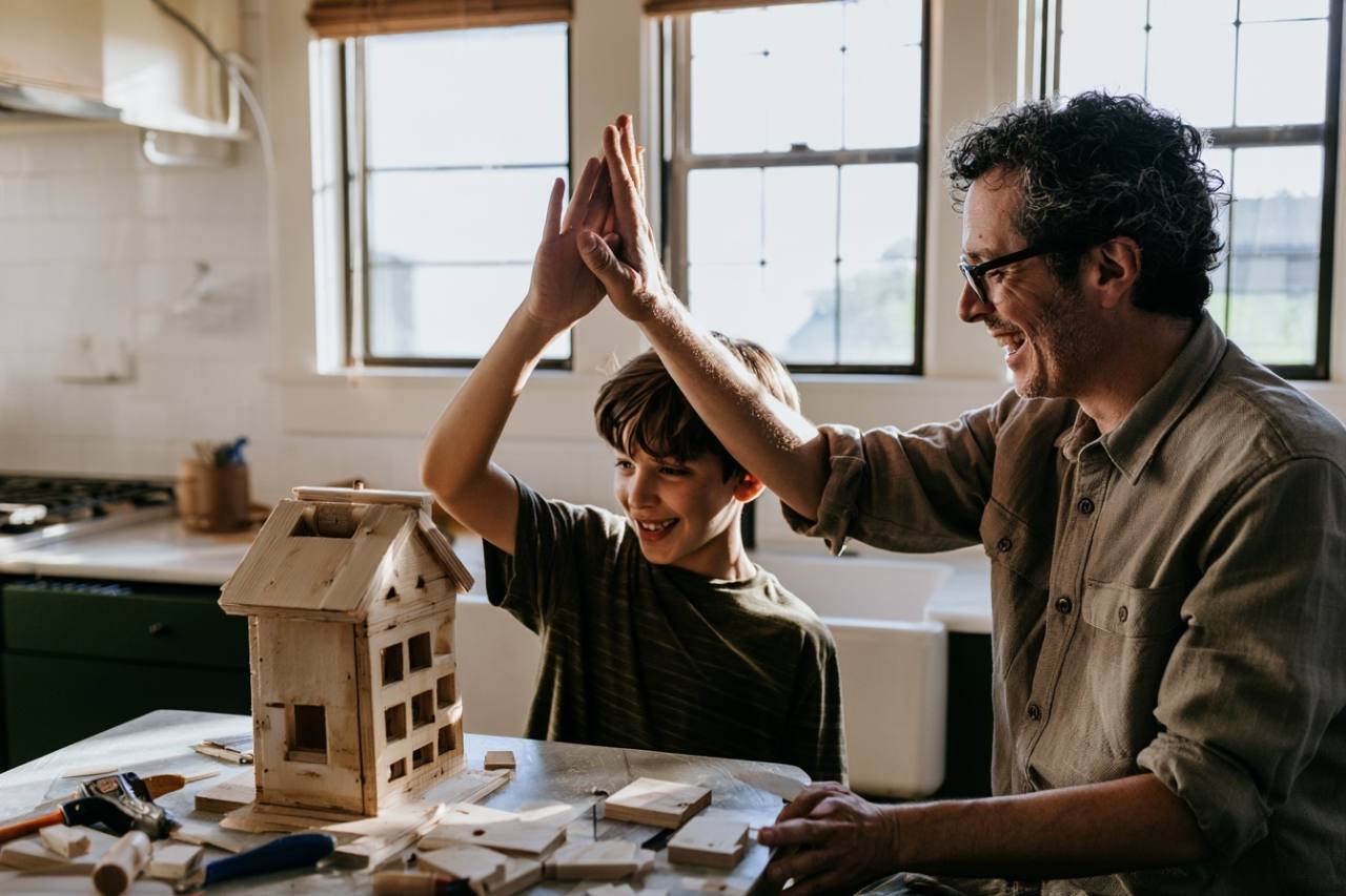 A parent and child high-five beside a wooden project they built